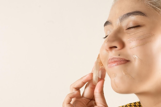 Femme tenant une éponge en silicone pour utiliser la base de maquillage