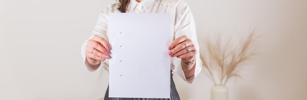 Femme tenant une feuille de papier vierge avec des coches Affiche de papier vierge dans les mains des femmes Modèle vierge pour les portefeuilles de graphistes Pour faire des plans dans les formations aux blogs d'entreprise