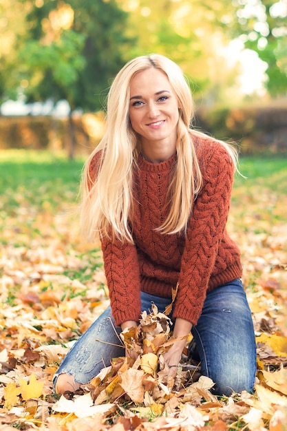 Femme tenant des feuilles d'érable dans le parc d'automne