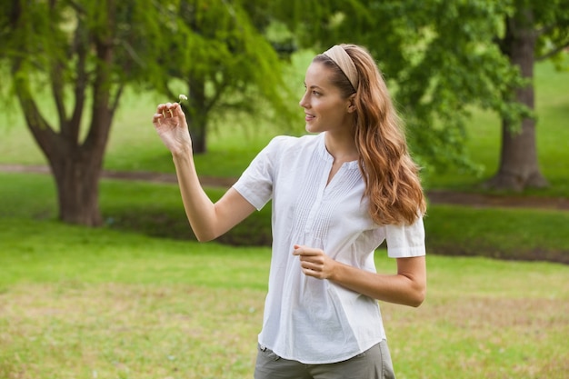 Femme tenant une fleur au parc