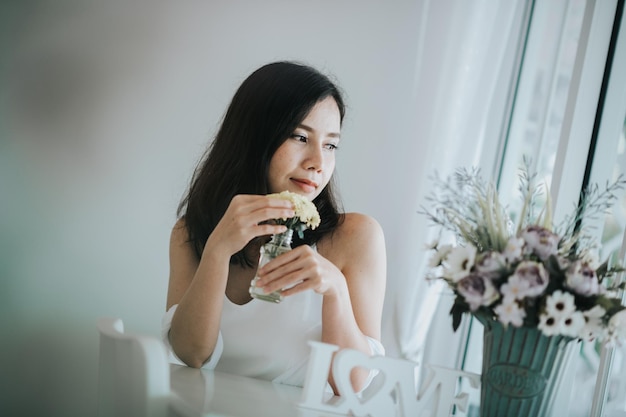 Femme tenant une fleur à la maison