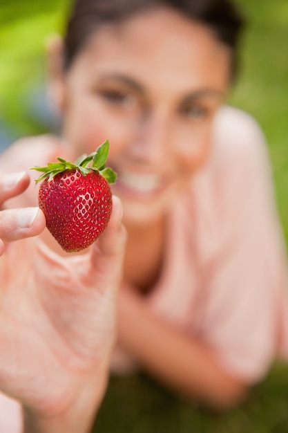 Femme tenant une fraise à portée de bras