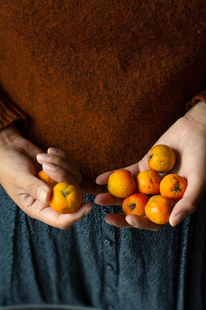 femme tenant des fruits tejocotes dans ses mains