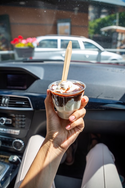 Femme tenant la glace mcdonalds mcflurry avec du chocolat dans une voiture après drive thru drive thru c...