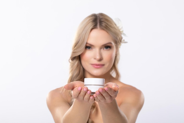 Une femme tenant gracieusement un produit de soins de la peau sur un fond propre et ordonné
