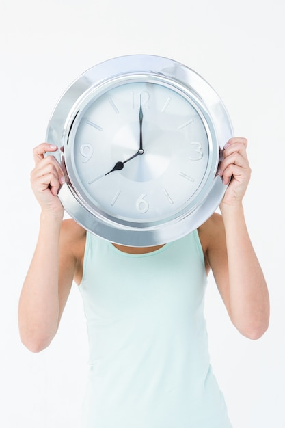 Femme tenant une horloge devant sa tête