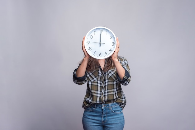 femme tenant une horloge sur entendre la tête sur blanc.