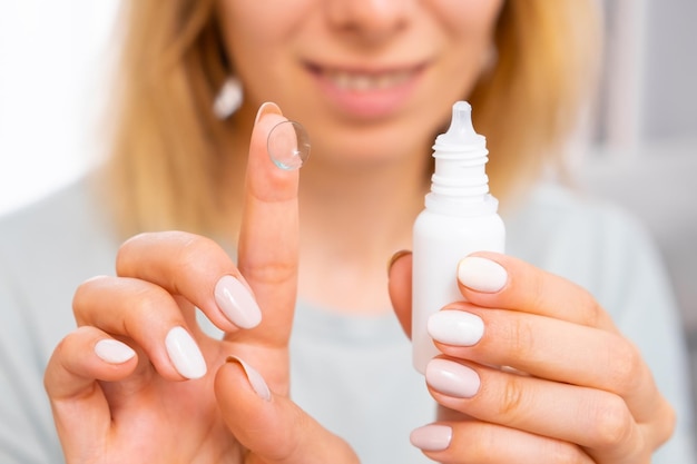 Femme tenant une lentille oculaire sur le doigt et des gouttes pour les yeux médecine et concept de soins oculaires