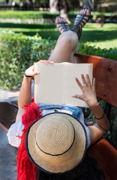 Photo une femme tenant un livre alors qu'elle est allongée sur un banc dans un parc