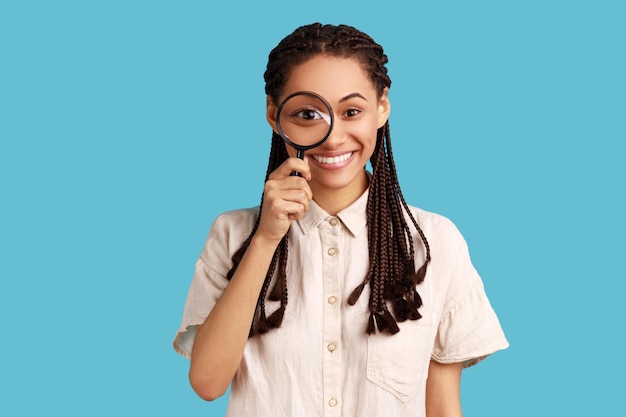 Femme tenant une loupe et regardant la caméra avec un grand visage positif pour les yeux zoom