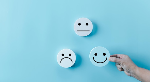 Une femme tenant la main, un visage heureux, un sourire, une icône de visage sur un objet bleu rond, une expérience client et un service avec satisfaction, un concept de pensée positive, une évaluation de la santé mentale, une journée mondiale de santé mentale.