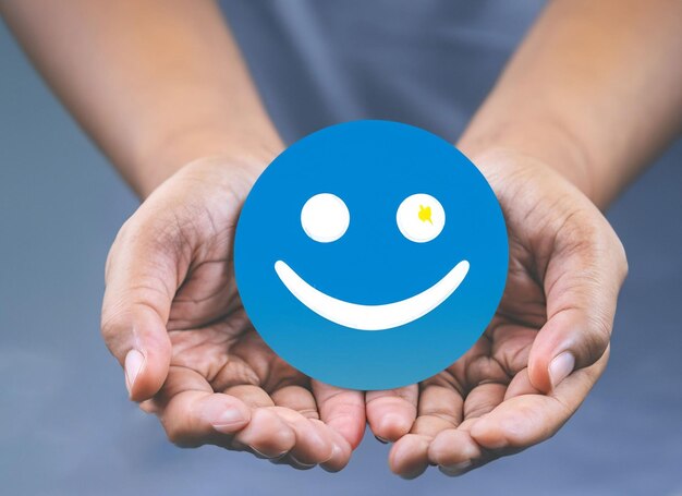 Une femme tenant la main, un visage heureux, un sourire, une icône de visage sur un objet bleu rond, un message positif sur la santé mentale.