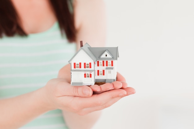 Femme tenant une maison miniature en position debout