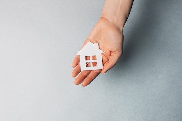 Femme tenant une maison de papier avec ses mains