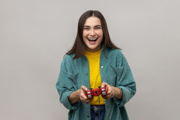 Femme tenant une manette de jeu gagnante du concours de jeux vidéo regardant la caméra avec une expression heureuse
