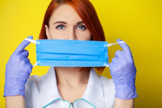 Femme tenant un masque pour couvrir la bouche et le nez pour se protéger contre le virus sur fond jaune.