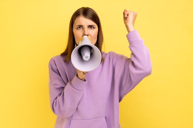 Femme tenant un mégaphone près de la bouche parlant fort en criant faisant une annonce avec le bras levé