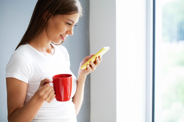 Femme tenant un message de saisie de smartphone discutant avec des amis sur les réseaux sociaux