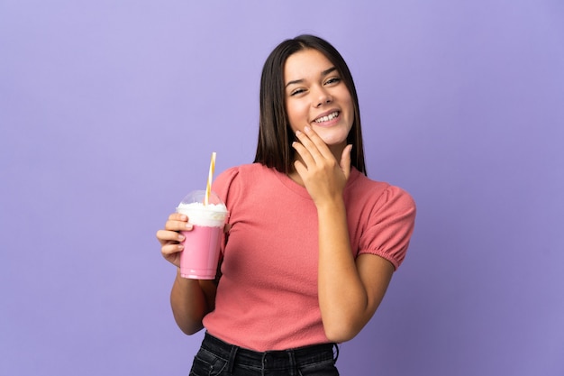 Femme tenant un milkshake aux fraises en levant tout en souriant