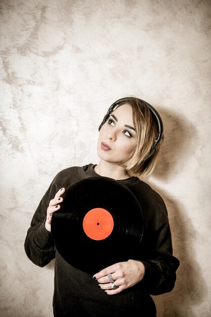 Femme tenant un mixeur de son alors qu'elle se tient contre le mur