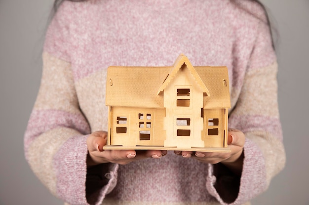 Femme tenant un modèle de maison en bois