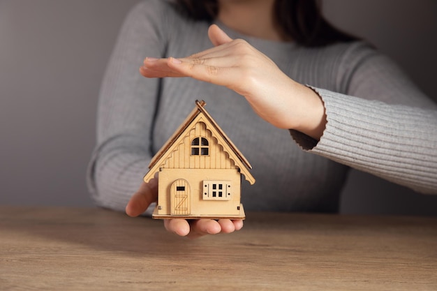 Femme tenant un modèle de maison dans ses mains