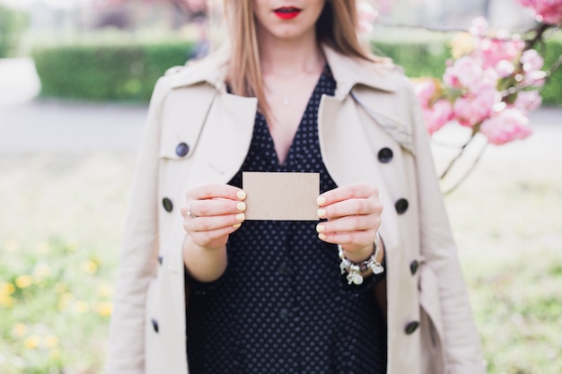 Femme tenant et montrant une carte de visite vierge sur la nature en plein air