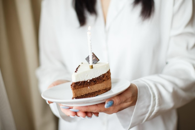 Femme tenant un morceau de gâteau avec une bougie