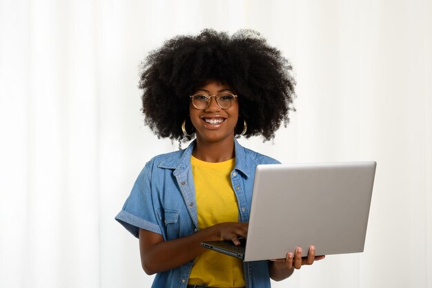 Photo femme tenant un ordinateur portable et tapant sur le clavier en regardant la caméra femme noire sur fond blanc