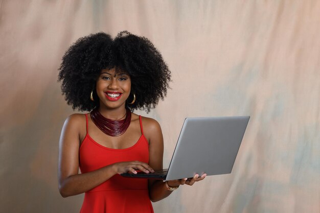 femme tenant un ordinateur portable tapant sur le clavier en regardant la caméra femme noire