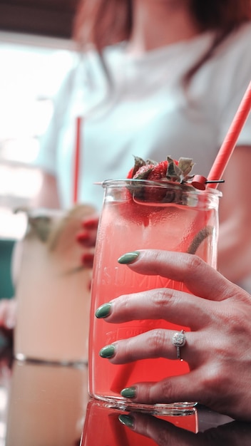 une femme tenant une paille devant une boisson rose