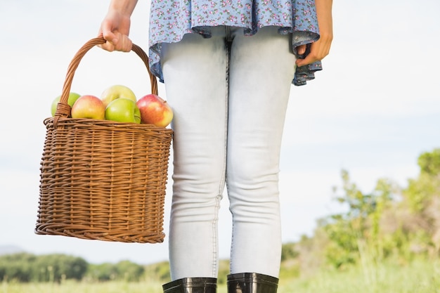 Femme tenant le panier de pommes