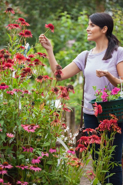 Femme tenant un panier tout en regardant les fleurs