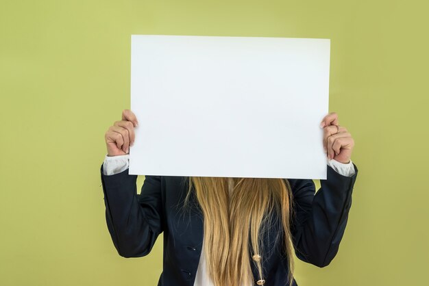 Femme tenant un panneau d'affichage vide sur fond vert