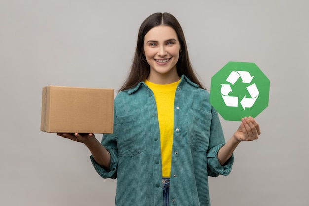 Femme tenant un panneau de recyclage vert et un emballage en carton économisant le concept d'écologie de l'environnement