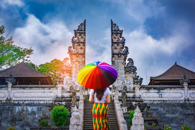 Photo une femme tenant un parapluie dans les portes du temple de lempuyang luhur à bali, en indonésie