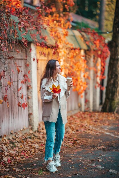 Une femme tenant un parapluie debout près des feuilles d'automne