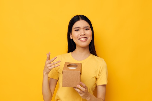 Femme tenant une petite boîte cadeau fond jaune