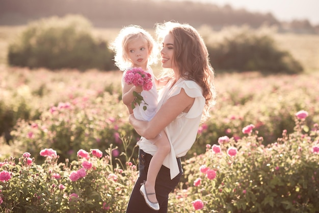 Femme tenant une petite fille dans un champ de roses