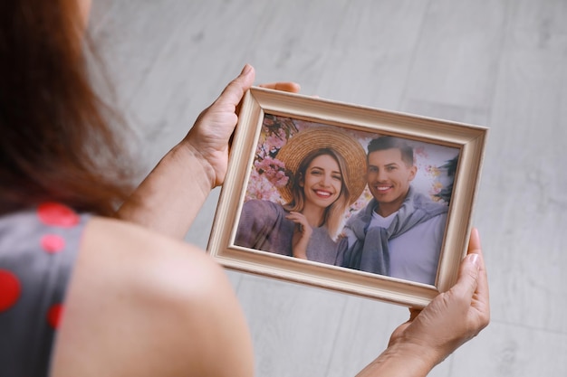 Femme tenant une photo encadrée d'un couple heureux à l'intérieur en gros plan