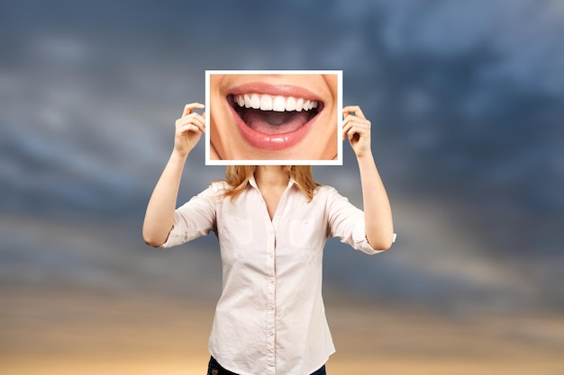 Femme tenant une photo avec un grand sourire. photo conceptuelle sur fond sombre