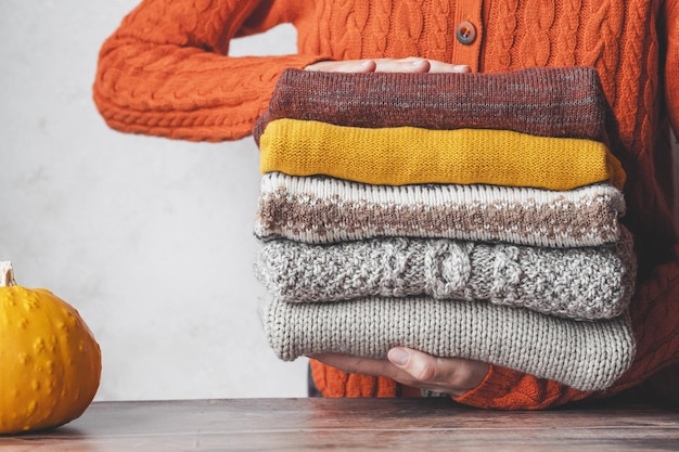 Une femme tenant une pile de chandails tricotés chauds d'automne. Changement de saison et de garde-robe. fas lent d'automne