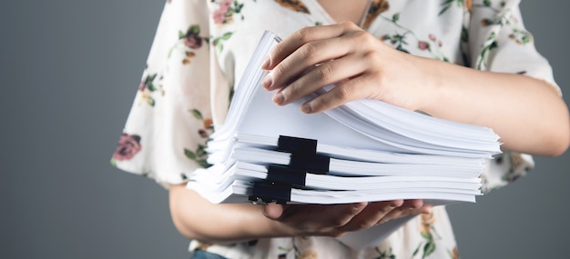 Femme tenant une pile de papiers dans ses mains