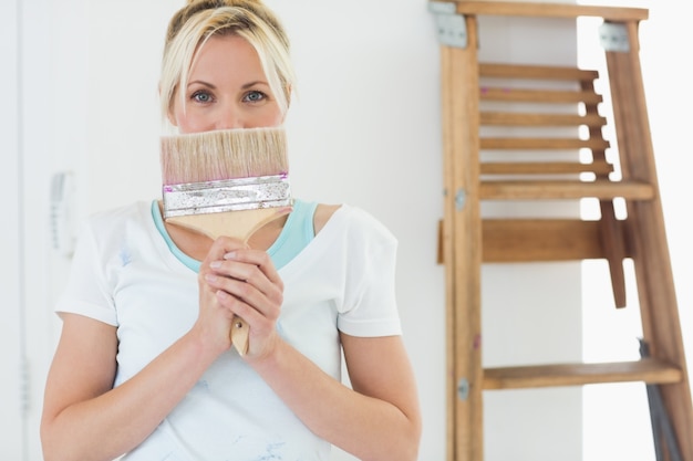 Femme tenant le pinceau devant le visage à la nouvelle maison