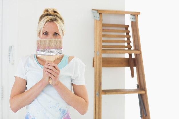 Femme tenant le pinceau devant le visage à la nouvelle maison