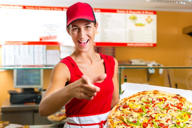 Femme tenant une pizza entière à la main