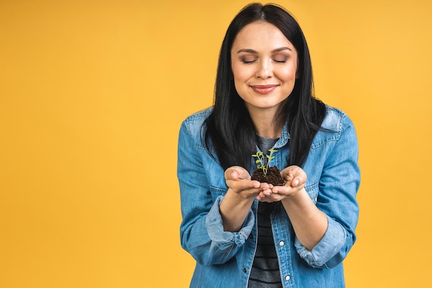 Femme tenant une plante verte dans la paume de sa main Femme tenant une jeune pousse fraîche