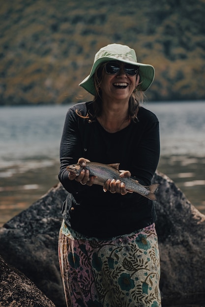 Photo femme tenant un poisson par une journée chaude et ensoleillée