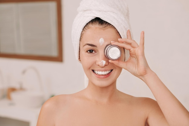 Femme tenant un pot de crème pour le visage