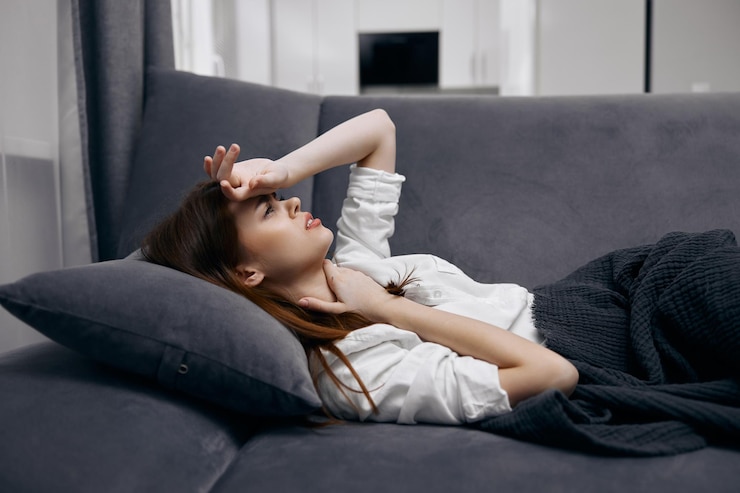 Photo femme tenant sa main sur son front allongée sur le canapé se cachant derrière une couverture se sentant mal au repos